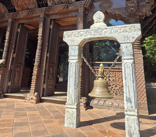 Decorative stone archway outside the carved Nepalese Peace Pagoda at South Bank, with a large bronze bell Hanging inside the archway.