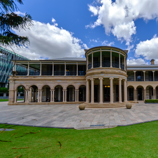 Grand old government house with columns, made in the Greek Revival style, set against a lush green lawn.