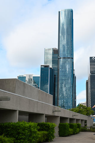 Concrete, low, brutalist Queensland Art Gallery building with glass high-rises towering behind it.