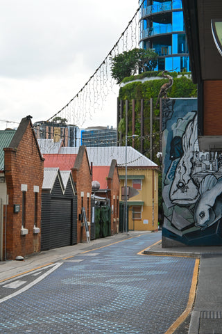 Fish Lane with heritage brick facades, modern glass high-rise, street art and fairy lights.