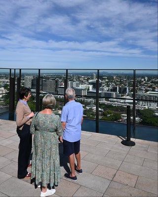 Guide and guests looking out over Brisbane and surrounds from high sky deck vantage point.