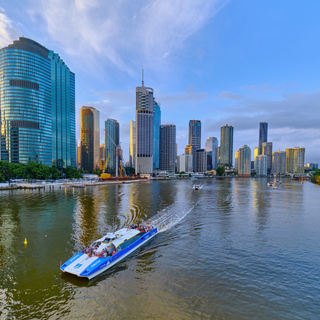 A view of Brisbane city skyline with the Brisbane River in the foreground featuring a City Cat ferry.